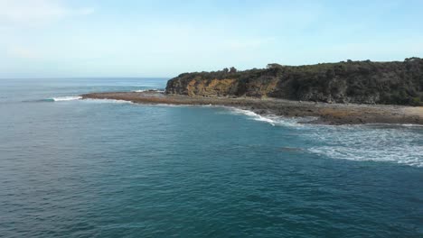 Forward-moving-aerial-shot-over-calm-ocean-reef-with-cliffs-on-Australia's-southern-coast