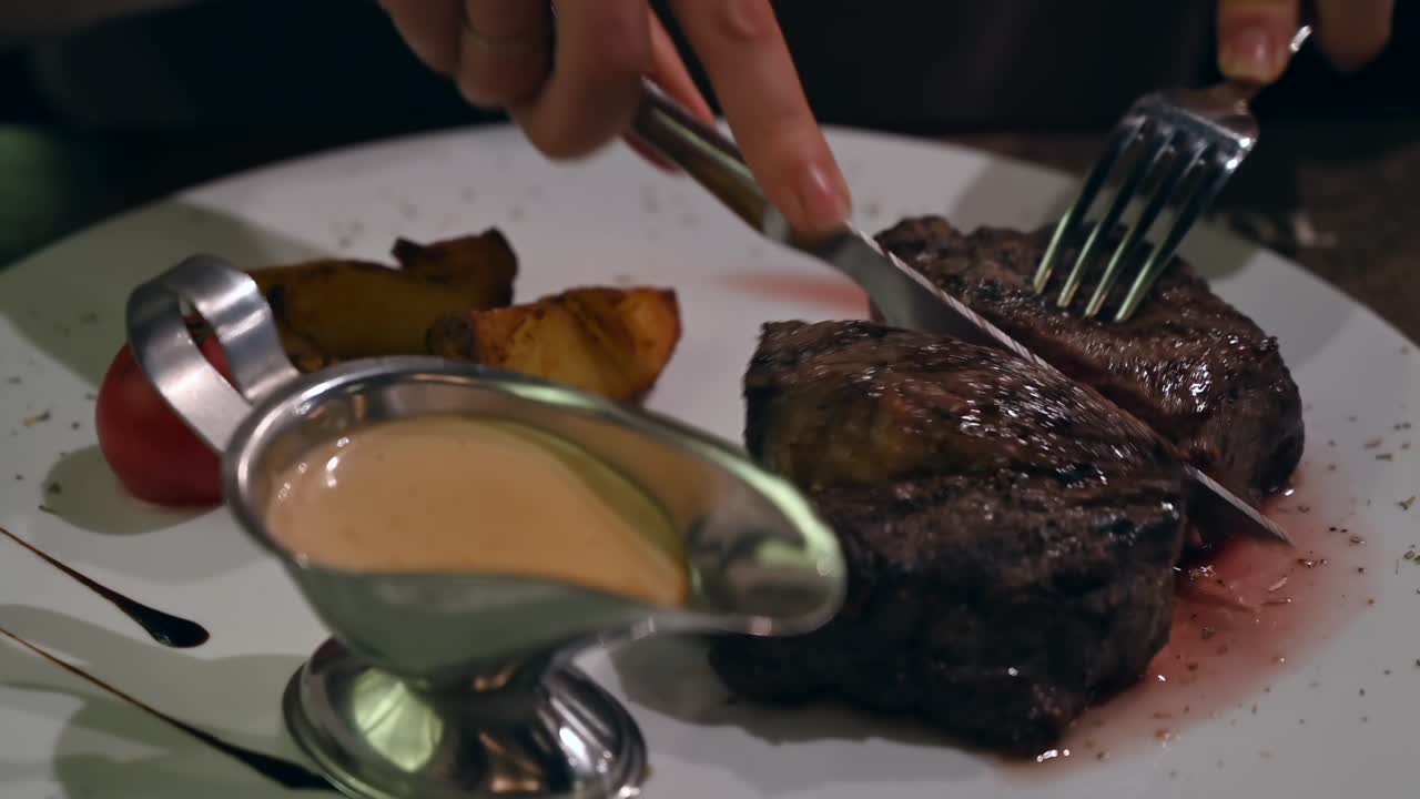 Primo piano di una donna che taglia un pezzo di bistecca al ristorante