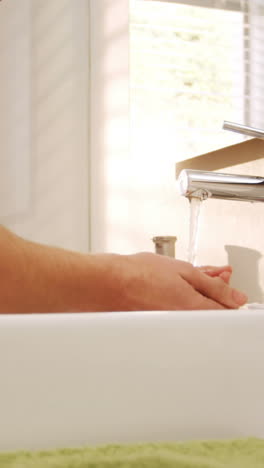 man washing his face with water in bathroom