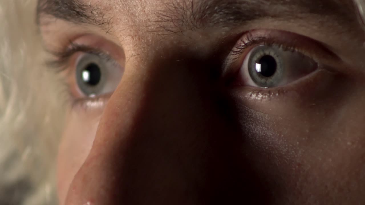 vicino di un giovane che sbatte le palpebre e guarda con paura negli occhi