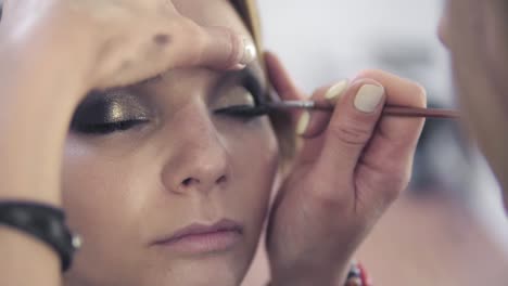 Vista-De-Cerca-Del-Maquillador-Aplicando-Sombra-De-Ojos-En-El-Párpado-Con-Una-Brocha-De-Maquillaje.-Maquillaje-Profesional.-Tiro-En-Cámara-Lenta