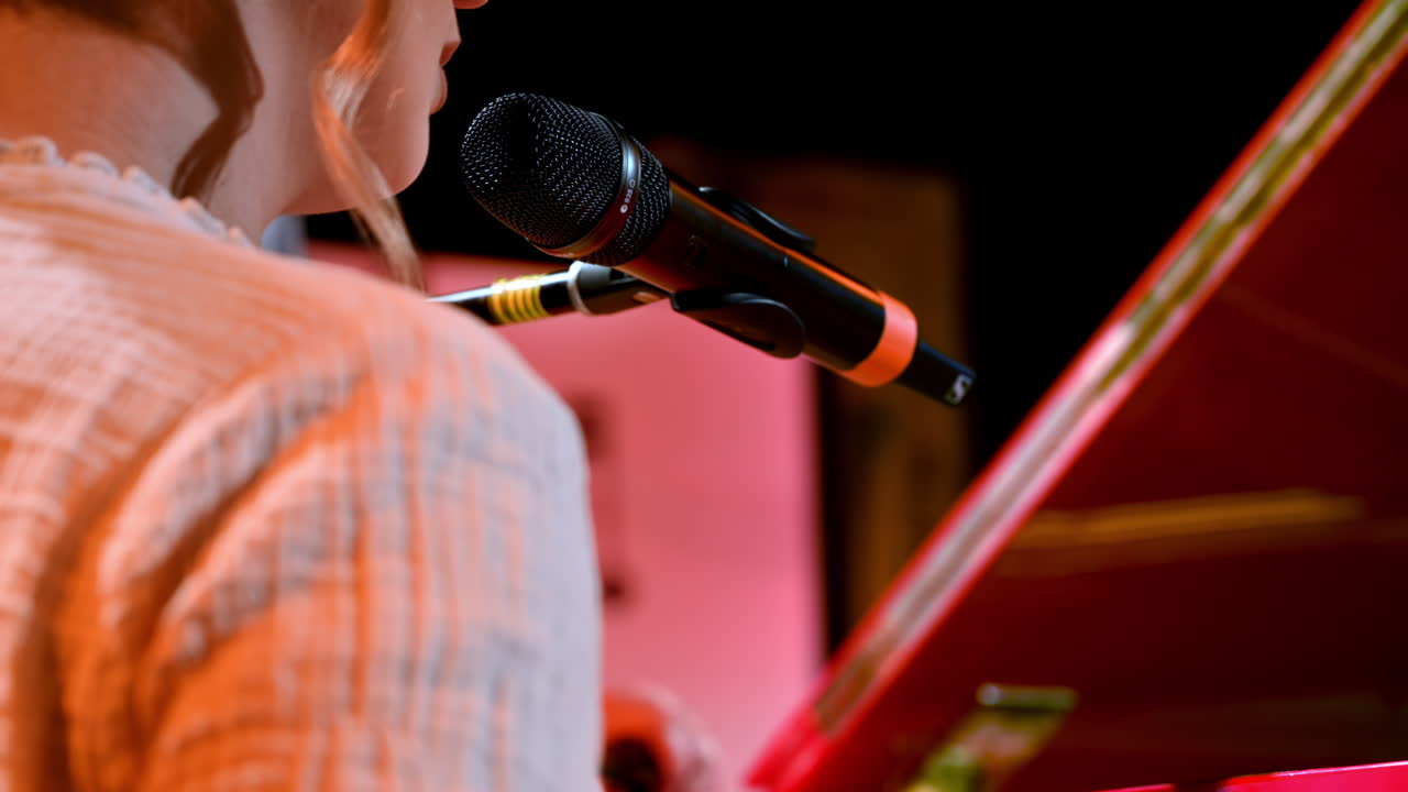 Woman singing into the microphone and playing a red piano