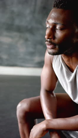vertical video: focused athlete resting after intense workout in gym, showing determination