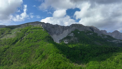 Drohnenflug-Entlang-Des-In-Den-Tieferen-Lagen-Mit-Wald-Bewachsenen-Berges-In-Richtung-Der-Höher-Gelegenen-Felsen