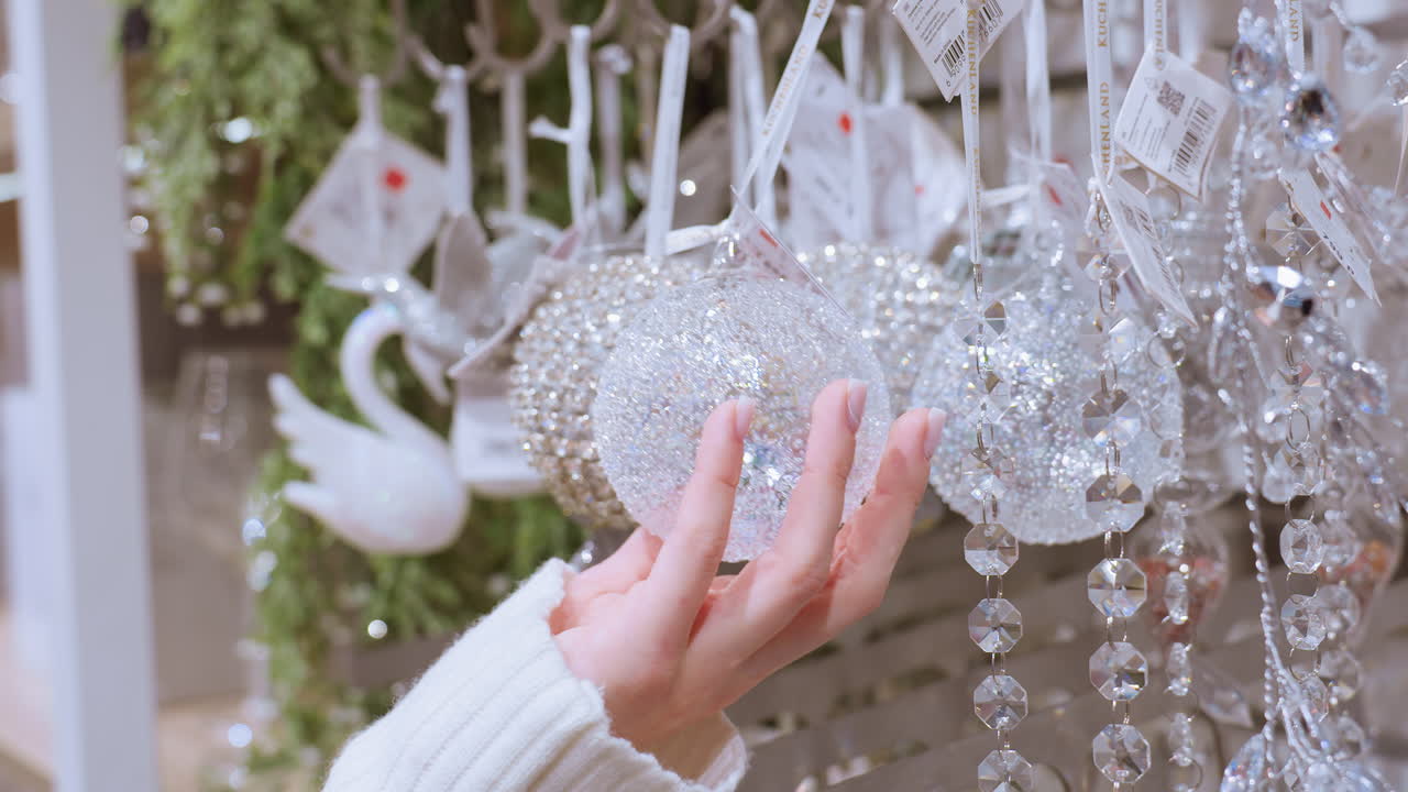 Close up of hand touching sparkling decorative material in home decor shop, beautiful glass ornaments and hanging decorations displayed for holiday season in retail store
