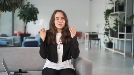 lovely-girl-talks-emotionally-and-cheerfully,-gesturing-while-looking-into-the-camera-with-the-office-in-the-background