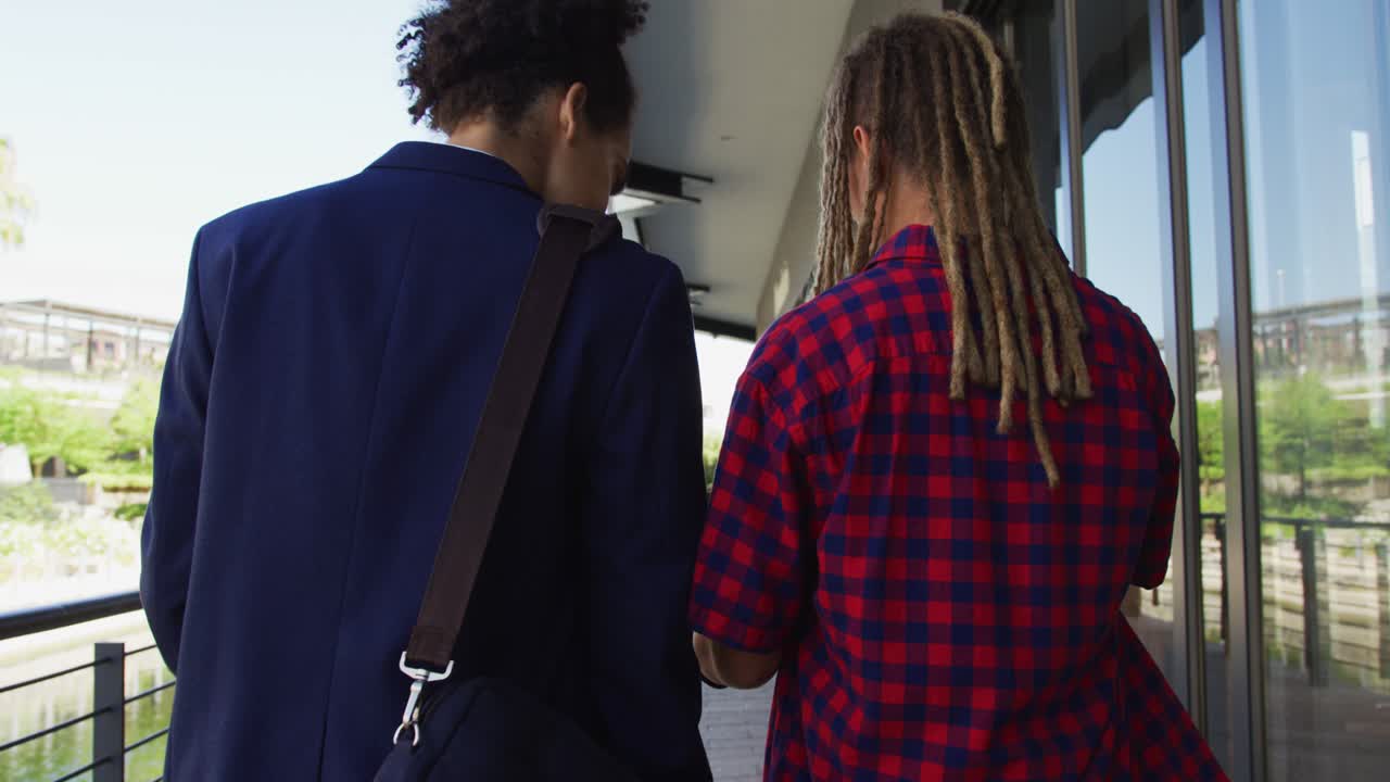 Two diverse male friends walking in the street looking at smartphone