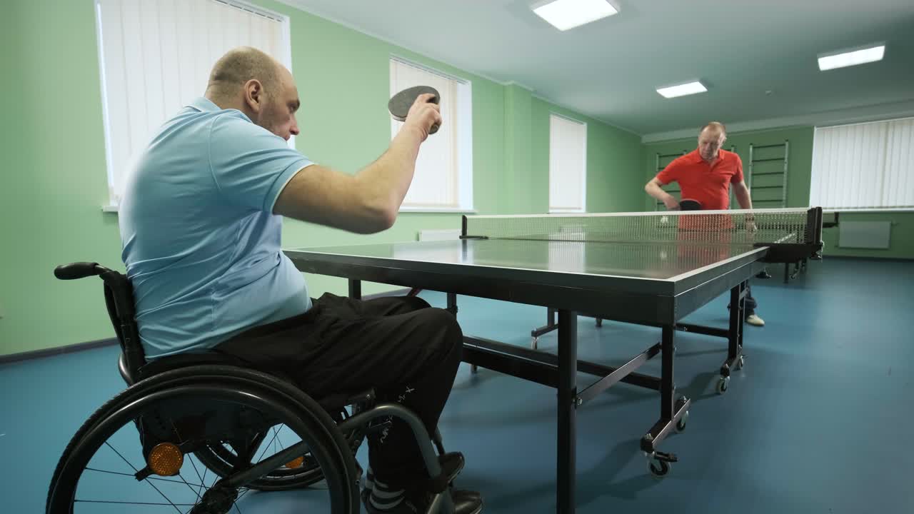 체어에 앉아 있는 남자가 핑핑을 하고, 장애인들이 탁구를 하고, 장애인의 재활, 패럴림픽 스포츠.