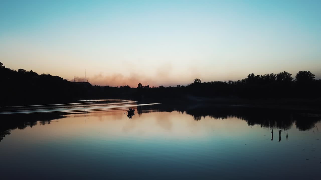 A gondolier is floating on a quiet river at sunset on a warm summer evening. Wonderful view. Slow motion. Camera motion to forward