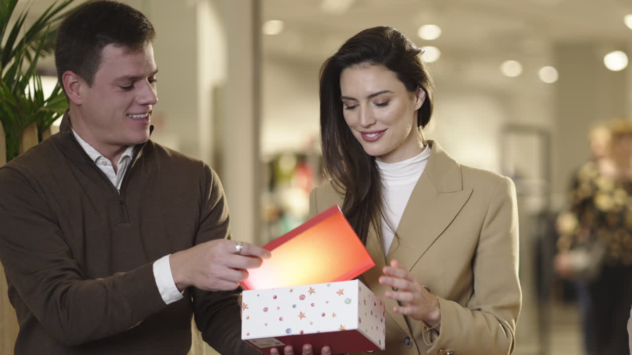 A happy couple exchanging a gift in a shopping mall