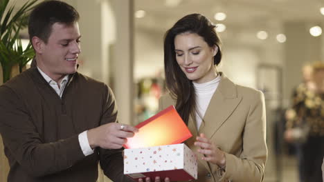 a happy couple exchanging a gift in a shopping mall