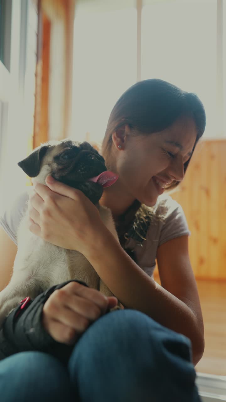 una chica acurrucando a un cachorro de pug