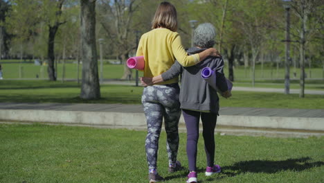 mujeres abrazándose unas a otras, sosteniendo colchonetas de yoga en las manos, hablando