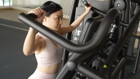 woman working out on a shoulder press machine in a gym