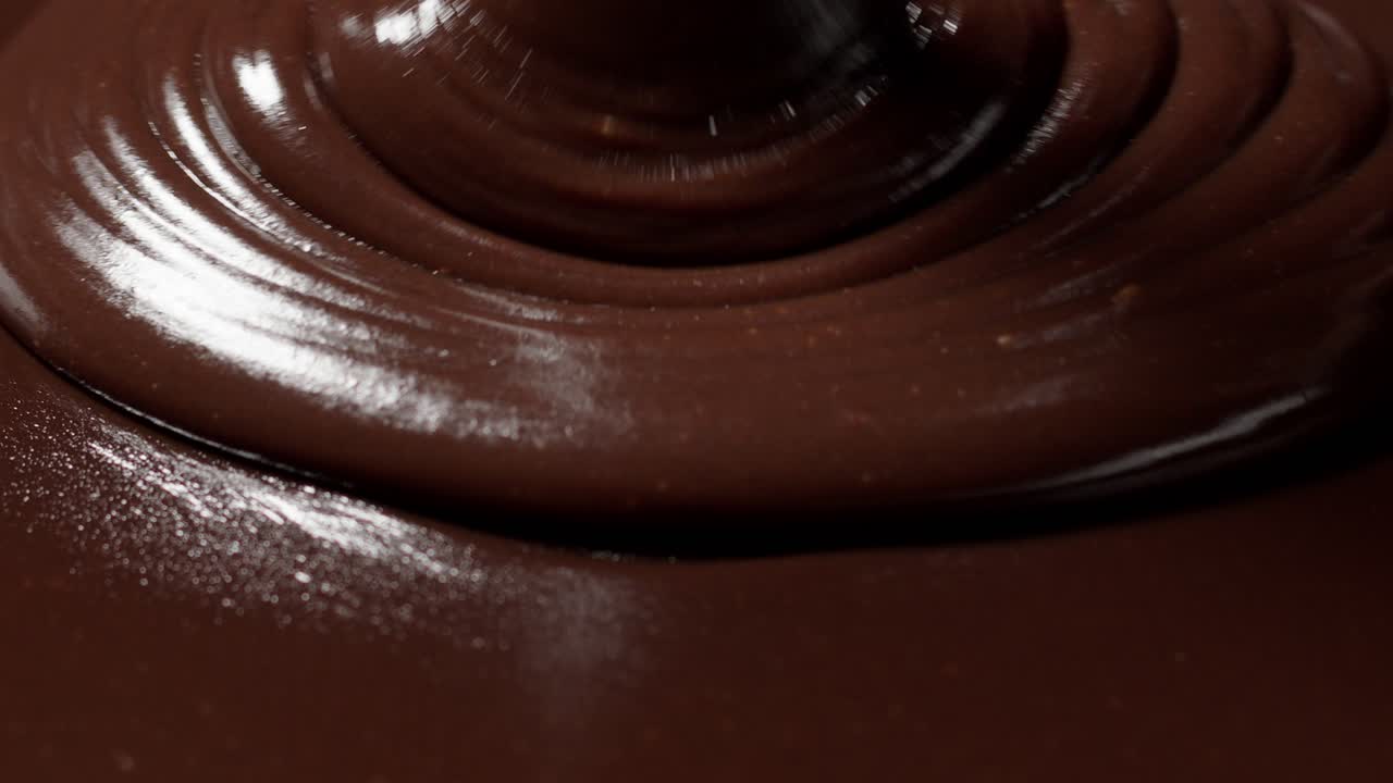 vertiendo chocolate oscuro o lechoso líquido derretido con nueces, el confitero prepara el postre, el glaseado