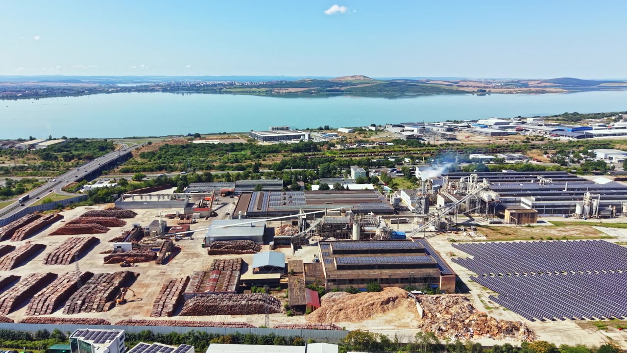 Factory site near the water with solar panels and storage area seen from high above in daytime