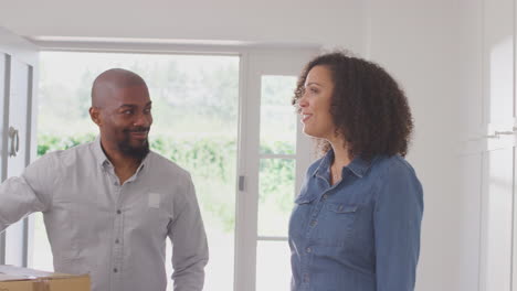 couple carrying boxes and hugging in hallway of new home on moving day