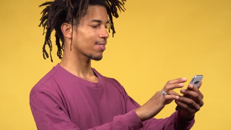 a cheerful young afro american man scrolling his phone