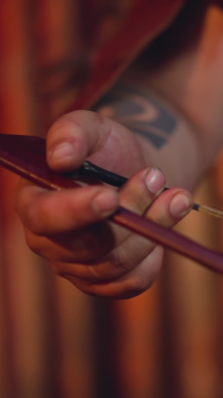 Man in leather clothes plays string instrument with bow at folk music concert on stage closeup. Altai musical instruments. Ancient culture and art