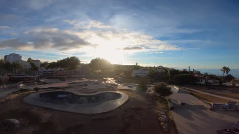 Warm-sunlit-public-skate-park-with-palm-trees-aerial-ascending-Birdseye-view