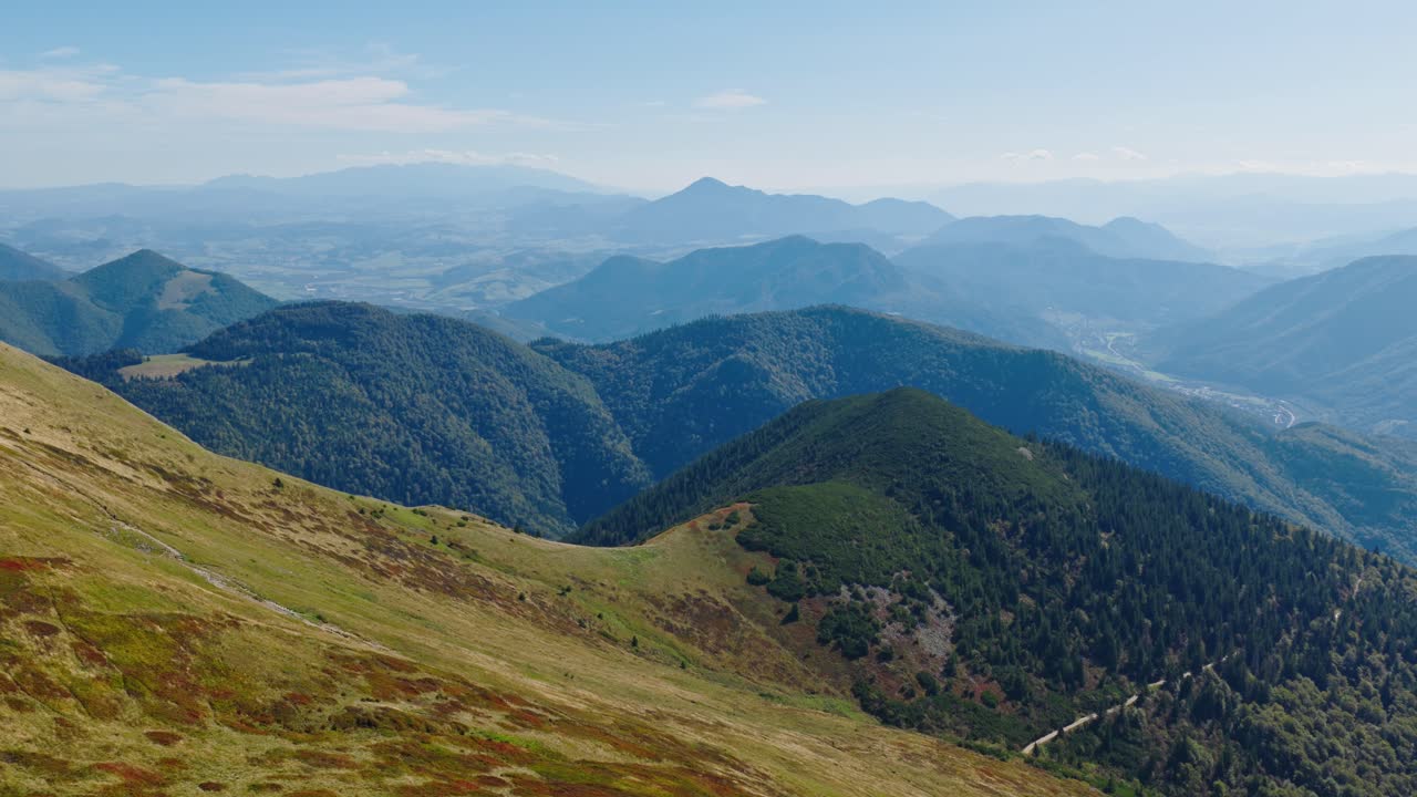 Imagem de drone do pico Chleb nas montanhas de Malá Fatra, Eslováquia, capturando colinas arborizadas onduladas, cordilheiras e vales distantes sob um céu azul claro. (vídeos em 4K)