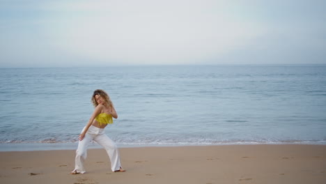 girl performing modern dance on evening ocean shore. woman dancer moving body