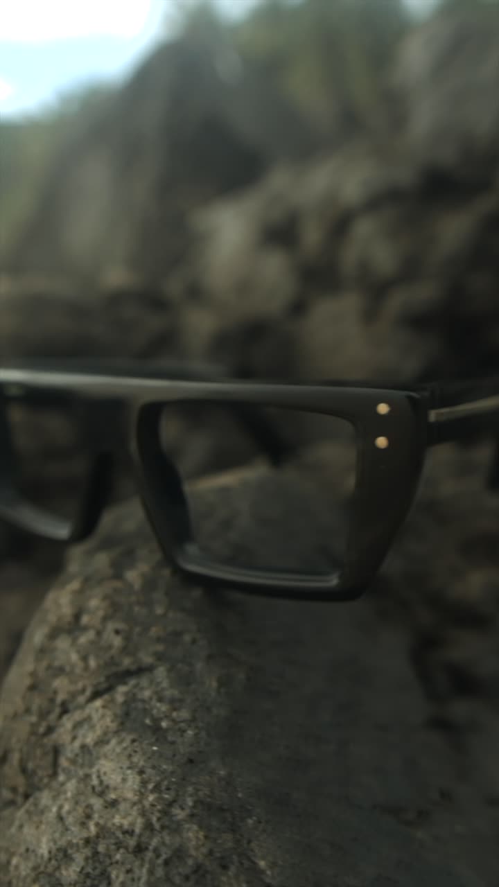 Glasses resting on a rock in a calm outdoor environment, with a focus on nature