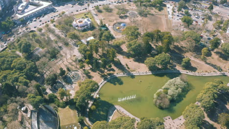 aerial - centenario park and its lake, buenos aires, argentina, spinning shot