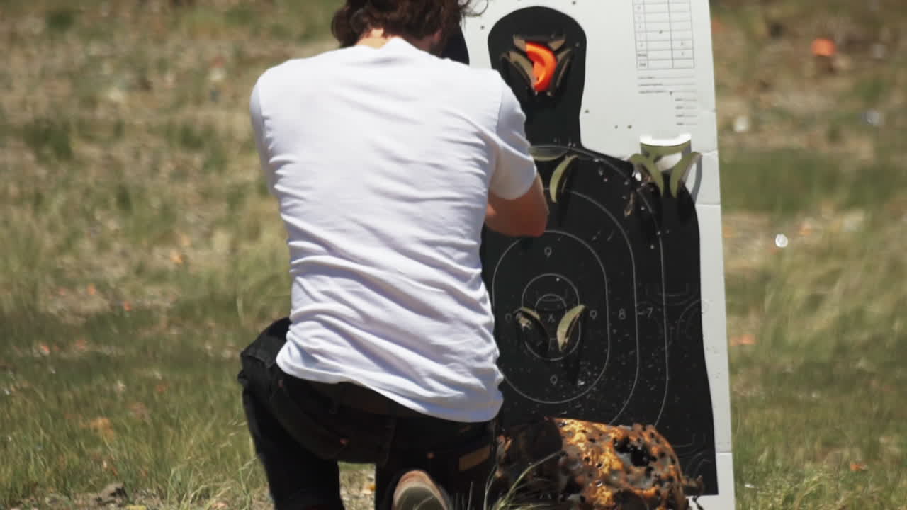 사격장에서 클레이 타겟 홀더를 웅크리고 검사하고 재설정하는 백인 남자