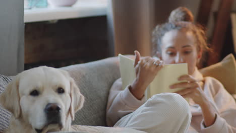 woman reading with dog on couch