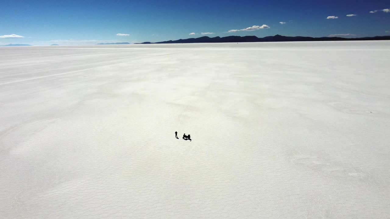 Motorcycle and rider tiny in vast expanse of salt flat, Uyuni Bolivia