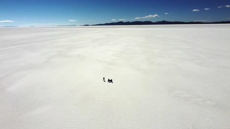 motocicleta y piloto pequeño en la vasta extensión de sal plana, uyuni bolivia