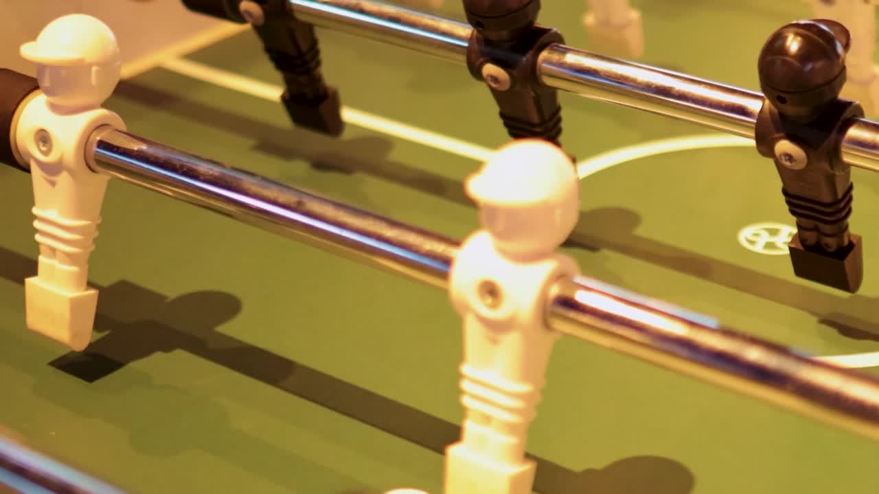 Detailed view of foosball rods and players in action, highlighting hand movements and game dynamics.