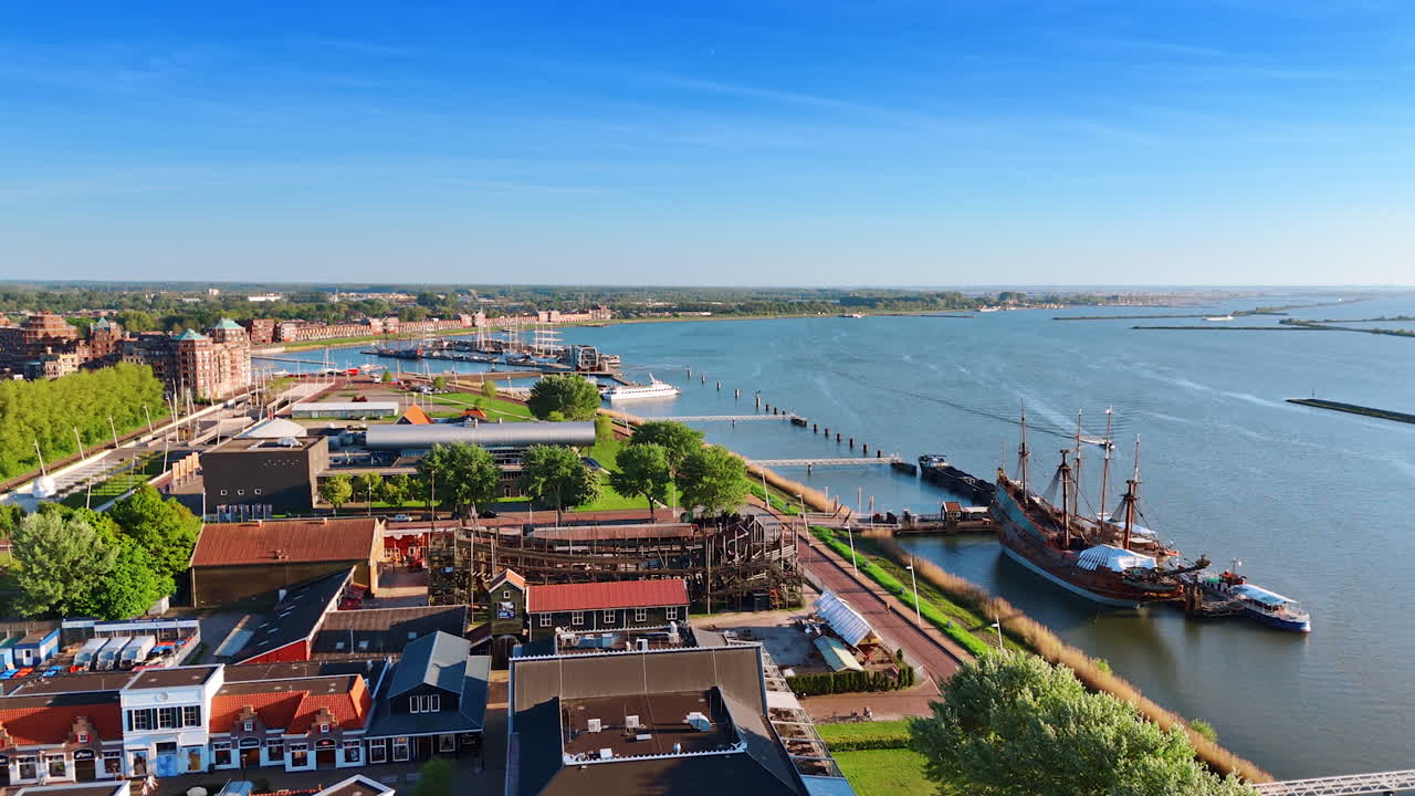 Flying closer to the reconstruction of the old ship Batavia in Batavialand Museum. Waterfront of Lelystad, the Netherlands on sunny day.