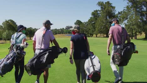 rear view of senior people wearing face masks walking with their golf bags at golf course