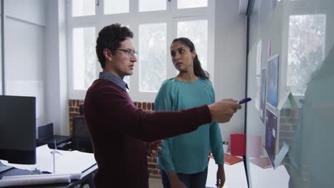 Man-and-woman-discussing-over-memo-notes-on-white-board-at-office