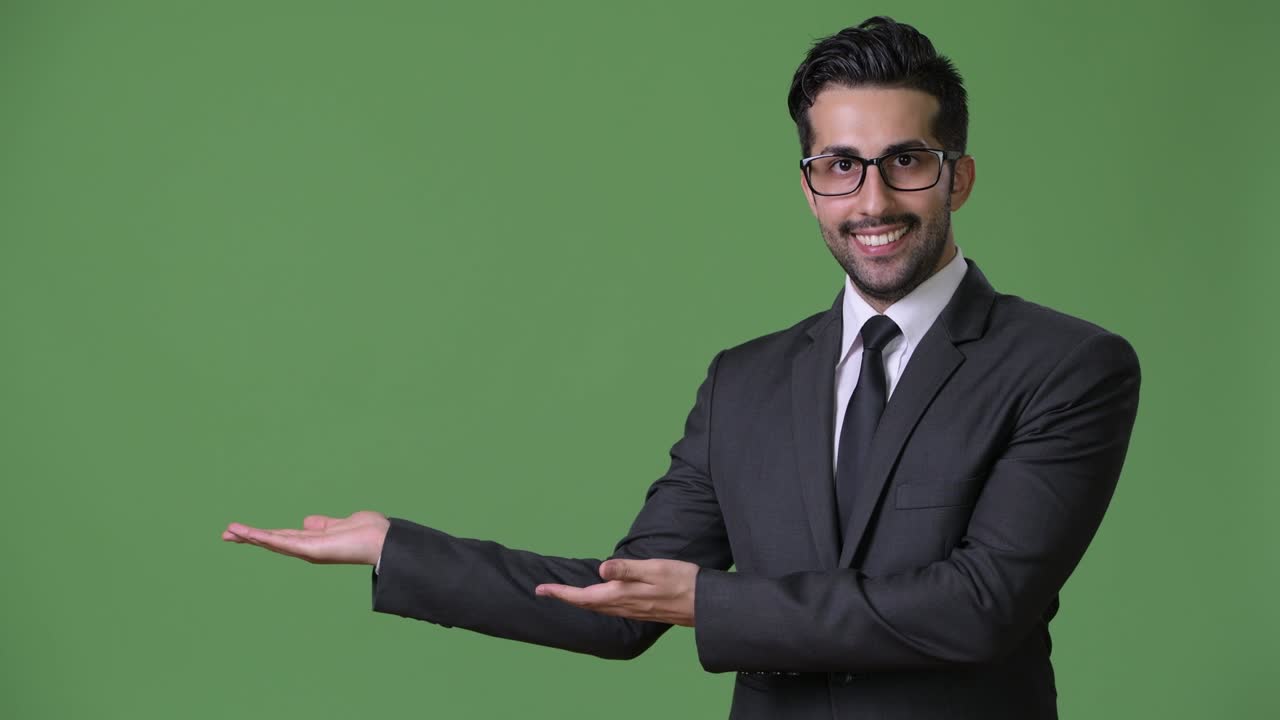 joven empresario persa barbudo y guapo contra un fondo verde