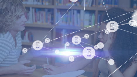 animation of network of digital icons over diverse girl and boy studying in library at college