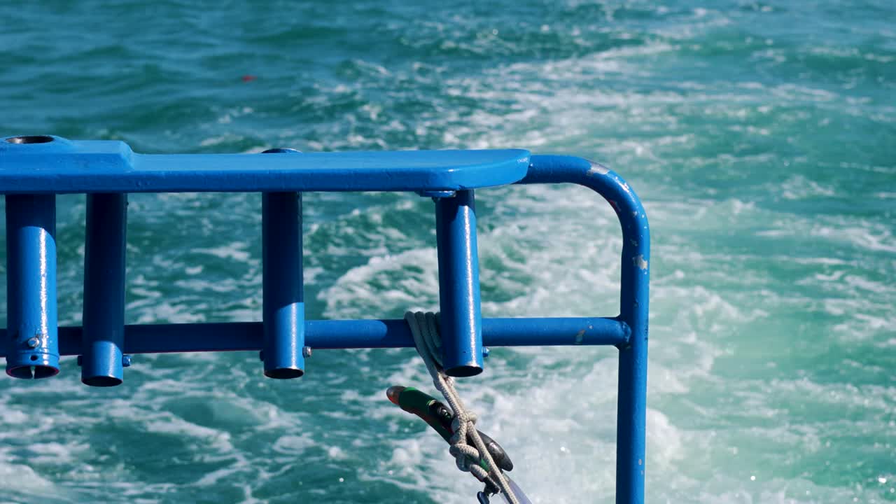 A fishing boat creates a wake in clear turquoise waters near Ko Racha Yai, Phuket, under bright sunlight