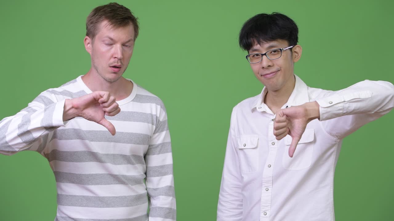 두 명의 슬픈 젊은 다민족 사업가들이 엄지손가락을 내려놓습니다.