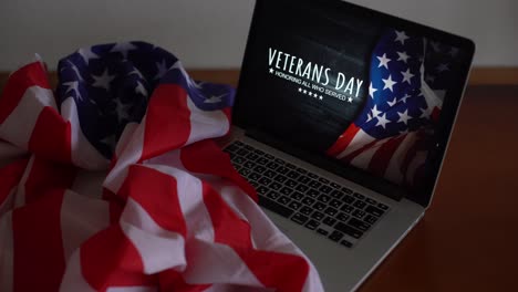 veterans day written in laptop with flag of the united states, on a rustic wooden background