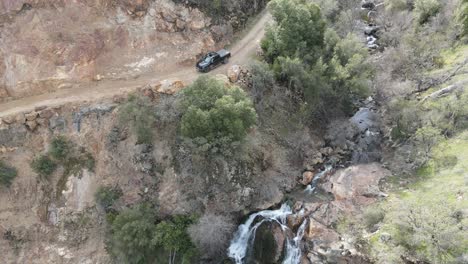 disparo aéreo de un avión no tripulado de una camioneta negra pasando por una cascada