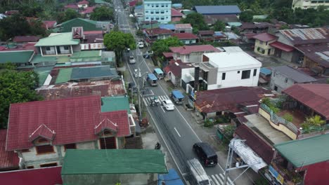 drone shot of small philippine road with cars passing by, surrounded by houses, trees, and powerlines