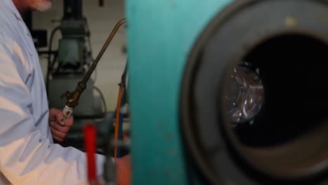 Side-view-of-mature-male-worker-creating--glass-in-glass-factory-4k