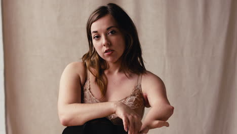 fotografía de estudio de una mujer natural con extremidad protésica en ropa interior promoviendo la positividad corporal en la silla