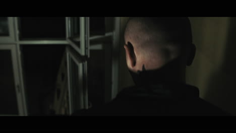 a bald dangerous looking man walks down the stairs