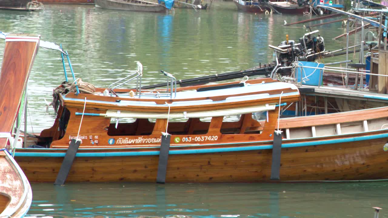 Carrellata di una tradizionale barca di legno thailandese che naviga in un porto tropicale a Krabi