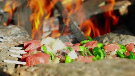 de cerca, brochetas en piedras rocosas cocinando en una fogata al aire libre
