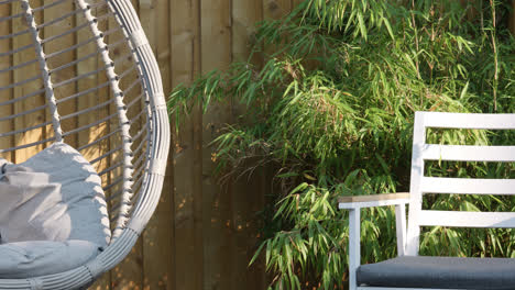 summer garden scene showing swing chair, garden chair and bamboo plants on a summers day