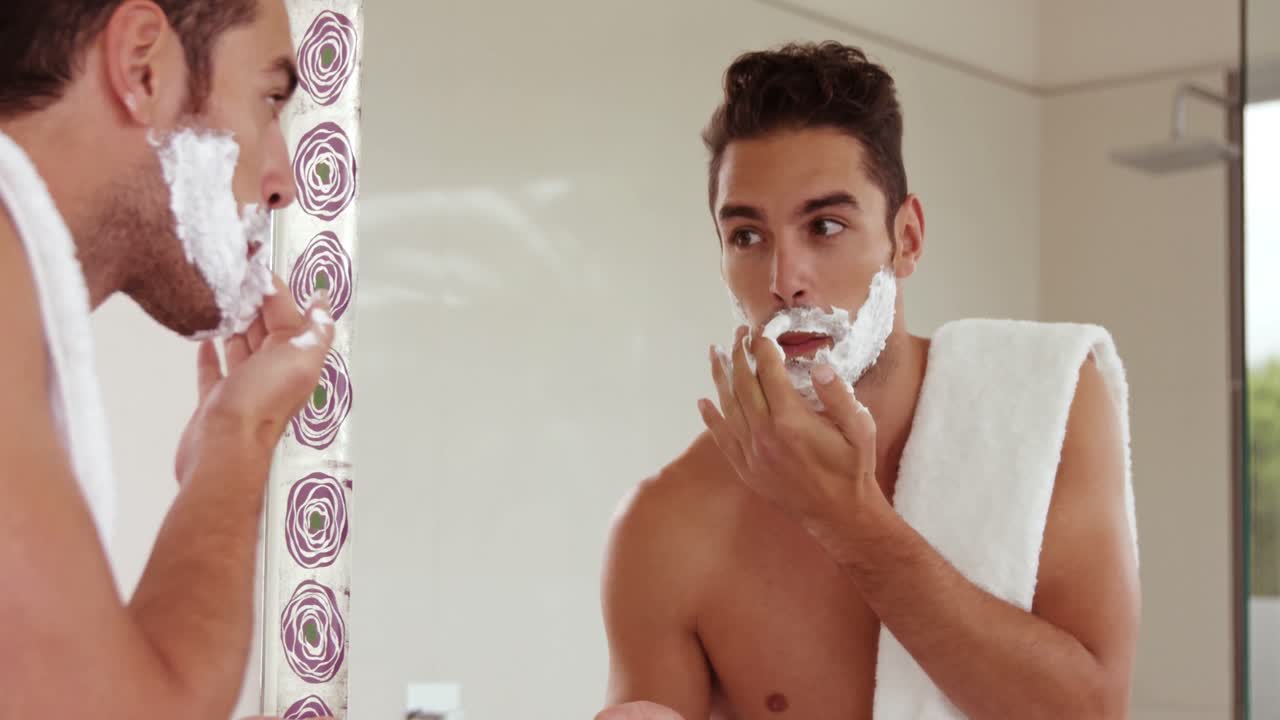 멋진 남자가 얼굴에 면도  ⁇ 을 쓰고 있다